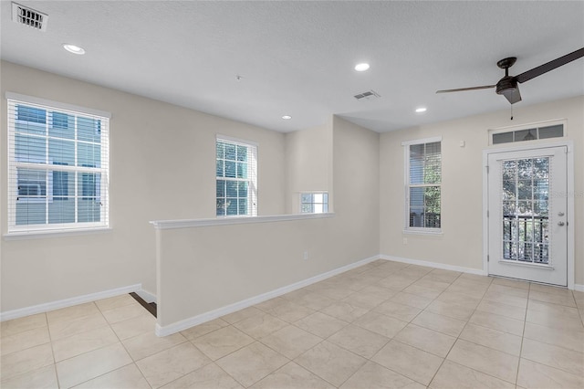 spare room with ceiling fan, a textured ceiling, and light tile patterned floors