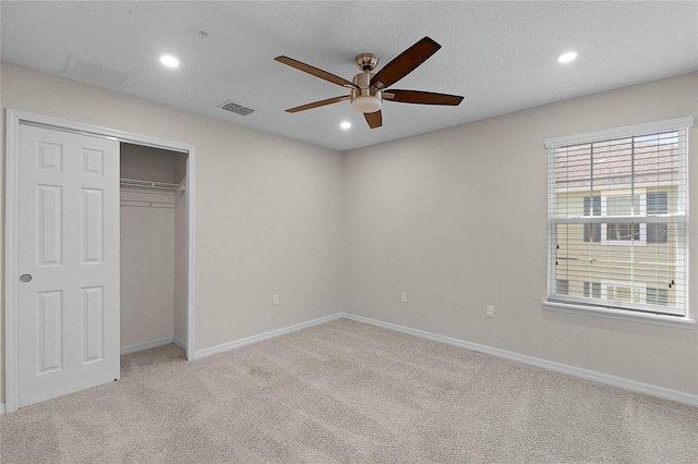 unfurnished bedroom with ceiling fan, light colored carpet, and a closet