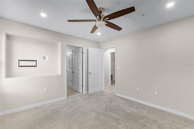 unfurnished bedroom featuring light colored carpet, a textured ceiling, and ceiling fan