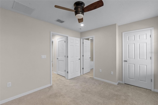 unfurnished bedroom featuring connected bathroom, light carpet, and ceiling fan