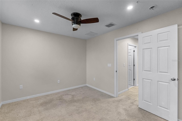 unfurnished room with a textured ceiling, light colored carpet, and ceiling fan