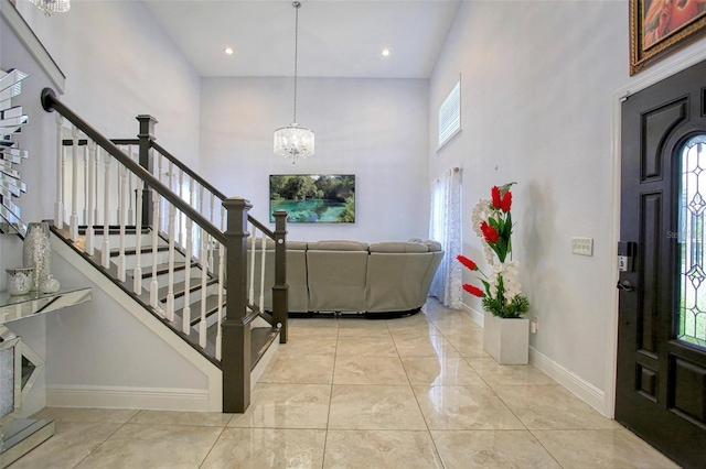 entryway with light tile patterned floors, a towering ceiling, and a chandelier