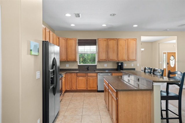 kitchen featuring a breakfast bar, sink, black refrigerator with ice dispenser, stainless steel dishwasher, and kitchen peninsula