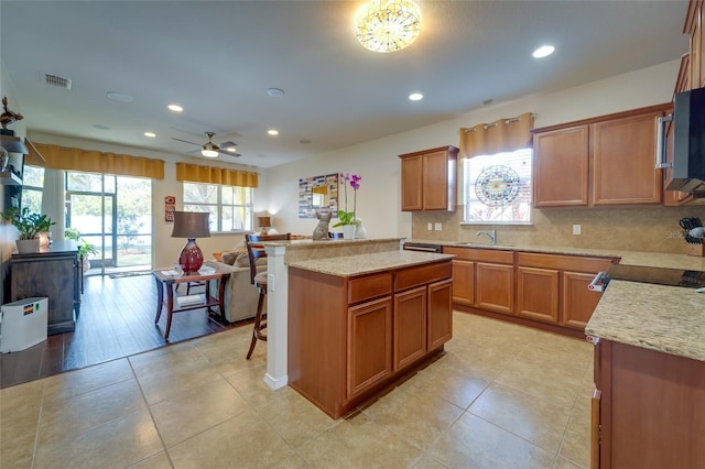 kitchen featuring a center island, a healthy amount of sunlight, light stone counters, and decorative backsplash