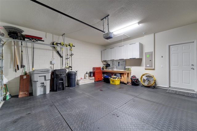 garage with a garage door opener, electric panel, and a workshop area