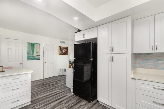 kitchen featuring dark hardwood / wood-style flooring, tasteful backsplash, white cabinets, and black fridge