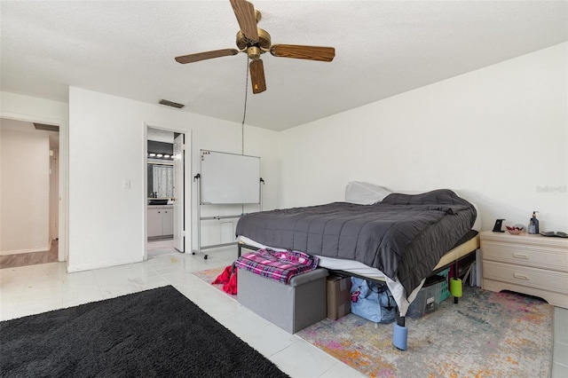 bedroom featuring light tile patterned flooring, ceiling fan, connected bathroom, and a textured ceiling