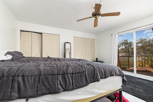 bedroom with two closets, access to outside, a textured ceiling, and ceiling fan