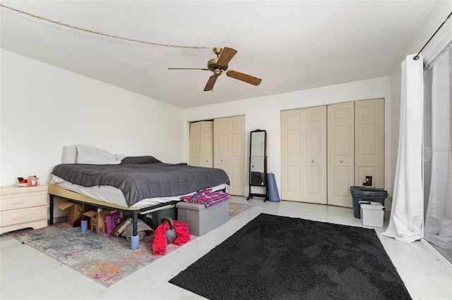 bedroom with ceiling fan, a textured ceiling, and multiple closets