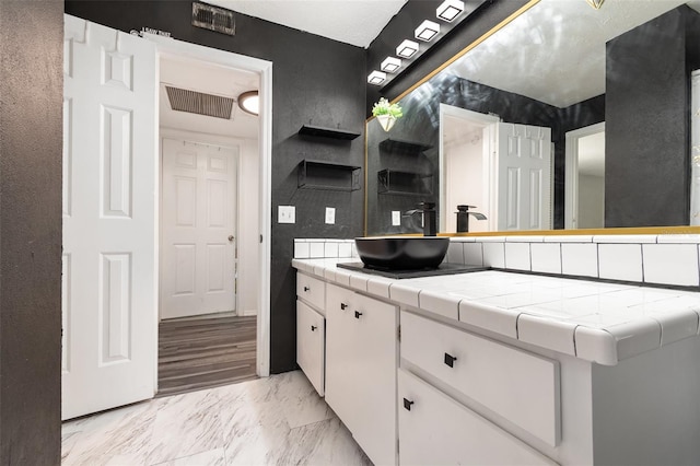 kitchen with white cabinetry, sink, and tile counters