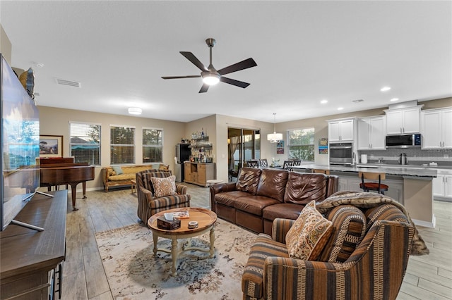 living room with light hardwood / wood-style flooring and ceiling fan