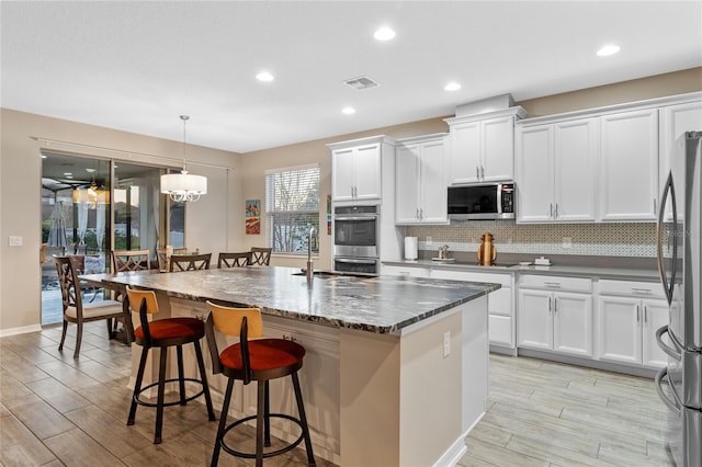 kitchen featuring sink, white cabinetry, hanging light fixtures, an island with sink, and stainless steel appliances