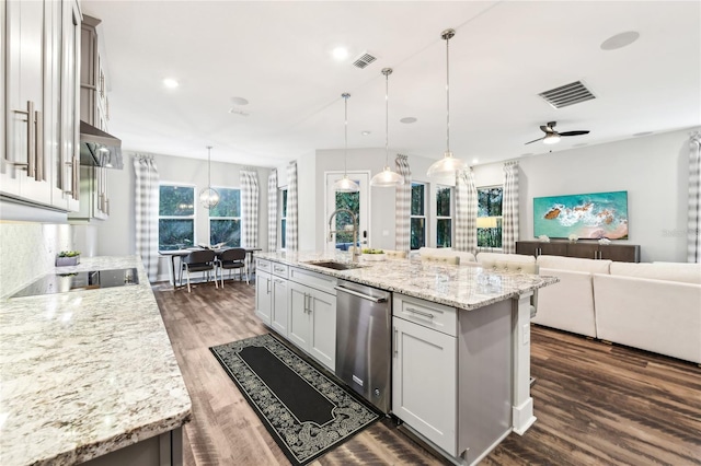 kitchen featuring sink, stainless steel dishwasher, hanging light fixtures, and a center island with sink