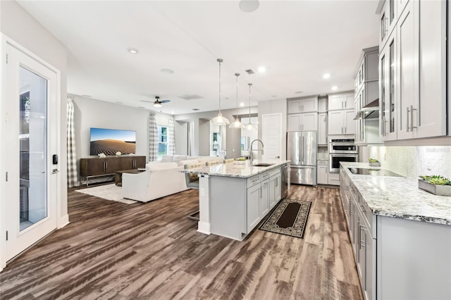 kitchen featuring a breakfast bar area, a center island with sink, appliances with stainless steel finishes, gray cabinets, and pendant lighting