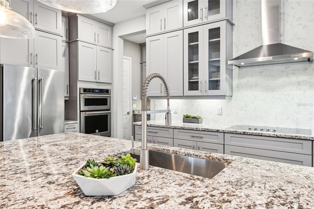 kitchen featuring wall chimney range hood, sink, appliances with stainless steel finishes, gray cabinetry, and tasteful backsplash