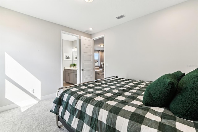 bedroom featuring light colored carpet and ensuite bathroom