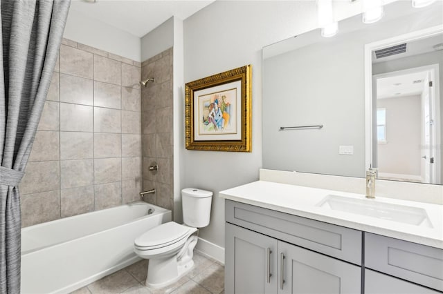 full bathroom with tile patterned flooring, tiled shower / bath, vanity, and toilet