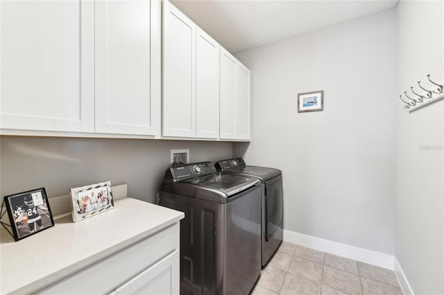 clothes washing area featuring cabinets, light tile patterned flooring, and independent washer and dryer