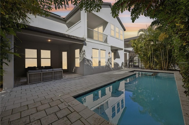 pool at dusk featuring an outdoor living space and a patio area