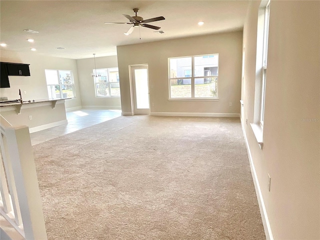 unfurnished living room featuring carpet floors, sink, and ceiling fan