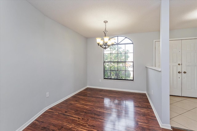 unfurnished dining area featuring dark hardwood / wood-style floors, a chandelier, and a textured ceiling