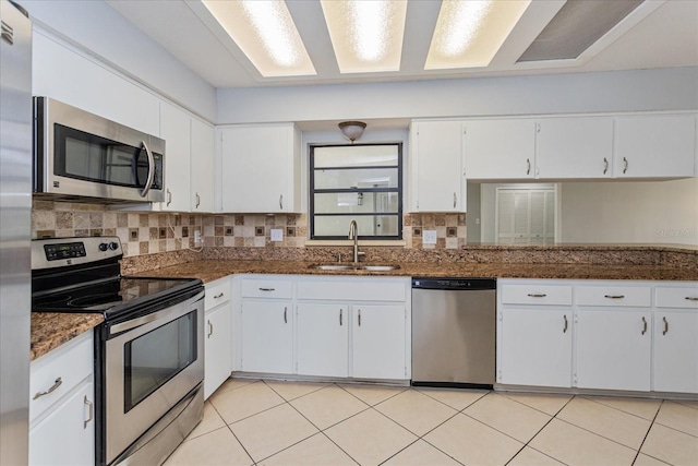 kitchen with stainless steel appliances, white cabinetry, sink, and dark stone counters