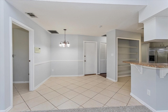 kitchen with white cabinetry, stainless steel fridge with ice dispenser, hanging light fixtures, light tile patterned floors, and kitchen peninsula