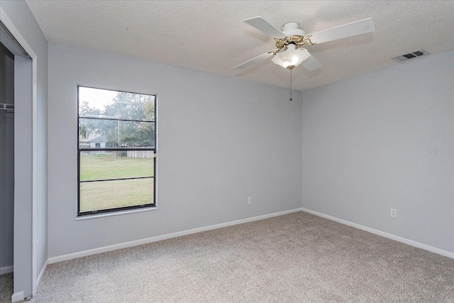 empty room with ceiling fan, carpet flooring, and a textured ceiling