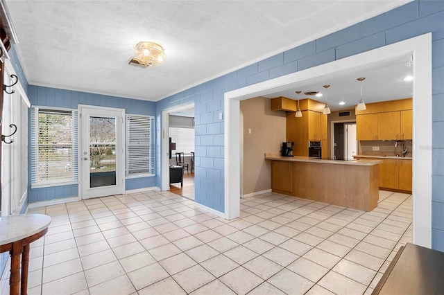 kitchen with light tile patterned flooring, kitchen peninsula, sink, and pendant lighting