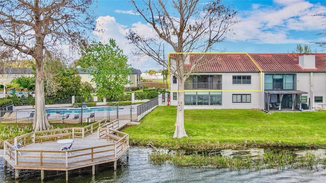 back of property with a fenced in pool, stucco siding, a lawn, fence, and a tiled roof