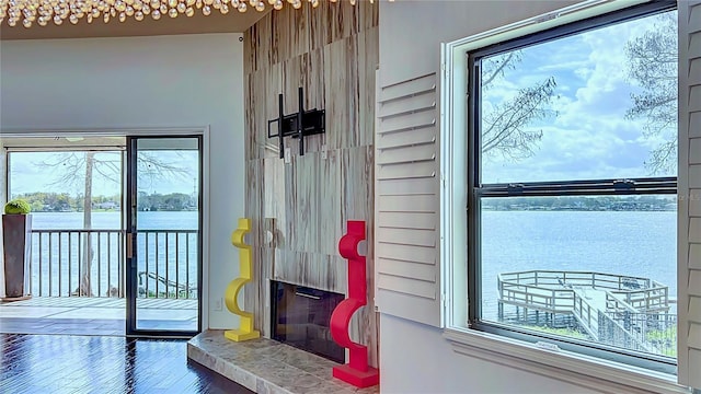 entryway with a tile fireplace, a water view, and wood finished floors