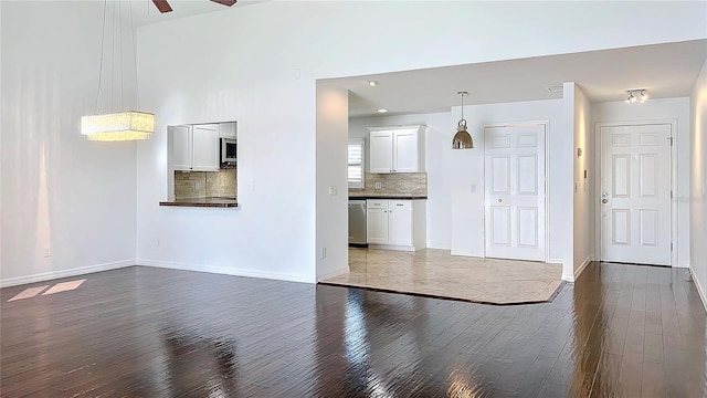 unfurnished living room featuring dark wood finished floors, baseboards, and ceiling fan