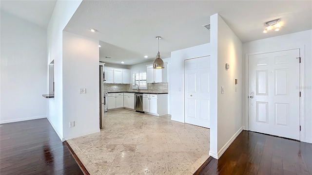 kitchen with white cabinets, dishwasher, dark countertops, light wood-type flooring, and backsplash