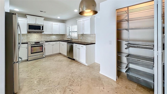 kitchen with tasteful backsplash, visible vents, white cabinets, stainless steel appliances, and a sink