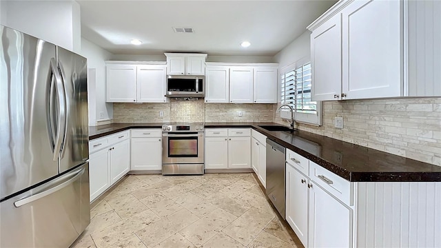 kitchen featuring stainless steel appliances, visible vents, backsplash, white cabinetry, and a sink