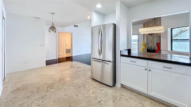 kitchen with decorative light fixtures, dark countertops, visible vents, freestanding refrigerator, and white cabinets