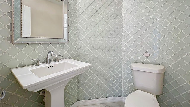 half bath featuring toilet and wallpapered walls