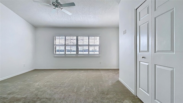 carpeted spare room with ceiling fan, baseboards, and a textured ceiling