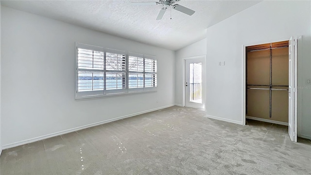 unfurnished bedroom featuring carpet, a closet, vaulted ceiling, a textured ceiling, and baseboards