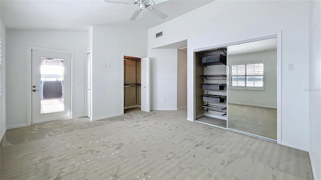 unfurnished bedroom featuring visible vents, baseboards, vaulted ceiling, carpet, and two closets