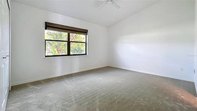 carpeted empty room with lofted ceiling, ceiling fan, and baseboards