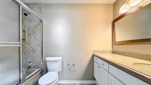 bathroom featuring baseboards, combined bath / shower with glass door, vanity, and toilet