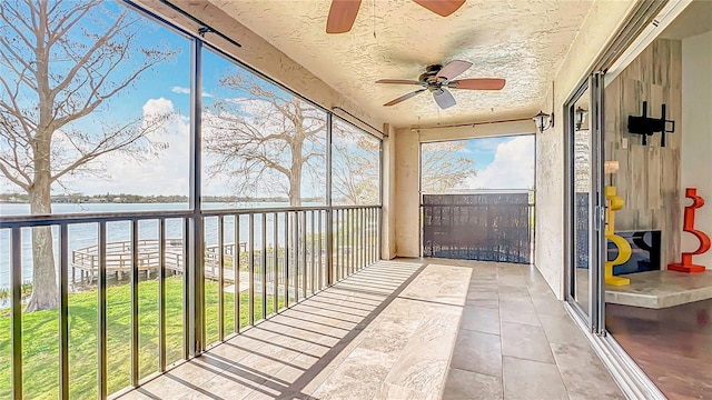 unfurnished sunroom with a water view and ceiling fan