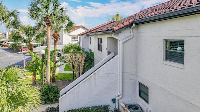 view of side of home with a tile roof and stucco siding