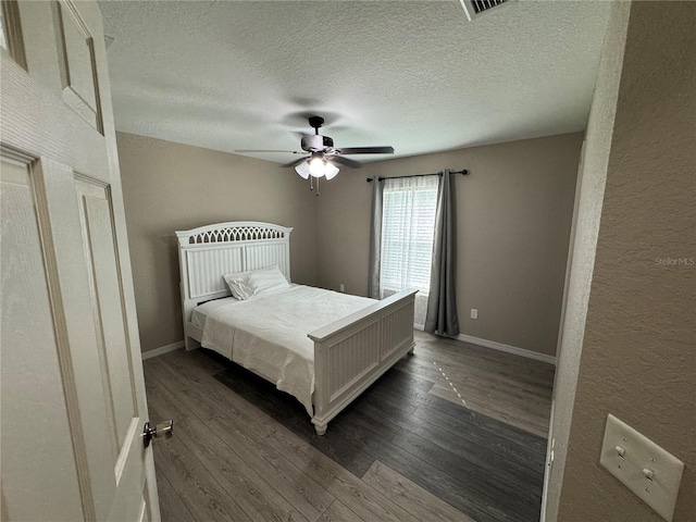 bedroom featuring ceiling fan, dark hardwood / wood-style flooring, and a textured ceiling