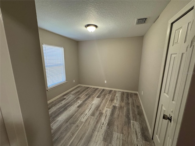 unfurnished room with a textured ceiling and dark hardwood / wood-style flooring