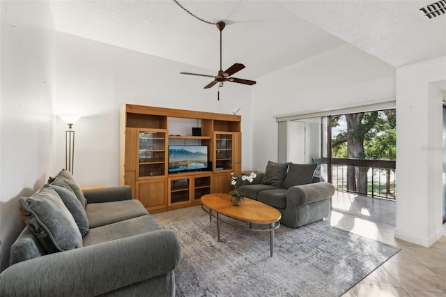 living room with a textured ceiling, ceiling fan, and light tile patterned flooring