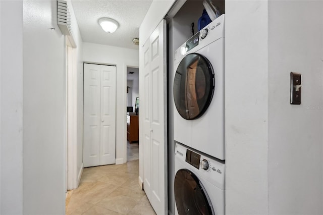 laundry room featuring stacked washer / dryer and a textured ceiling