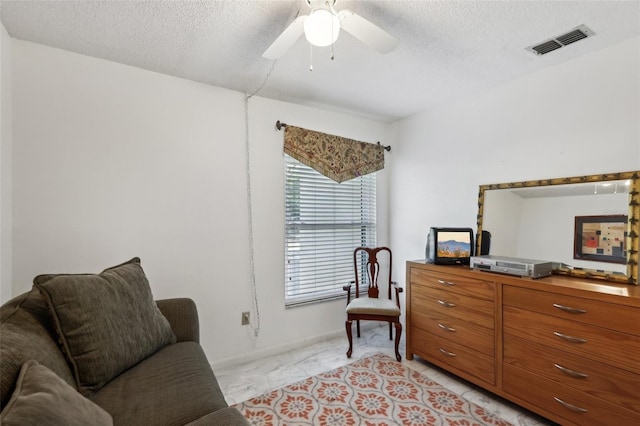 sitting room with a textured ceiling and ceiling fan