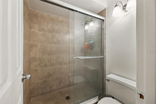 bathroom with toilet and a shower with shower door